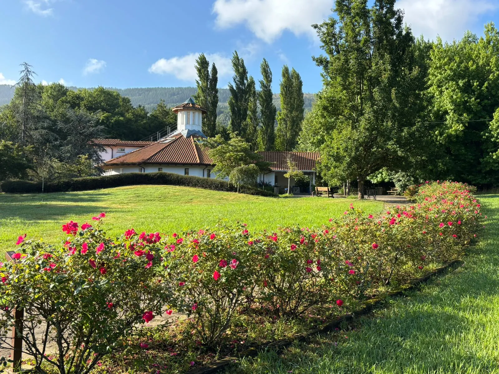 Amalurra’s stone building seen across a foreground of pink roses in bloom.